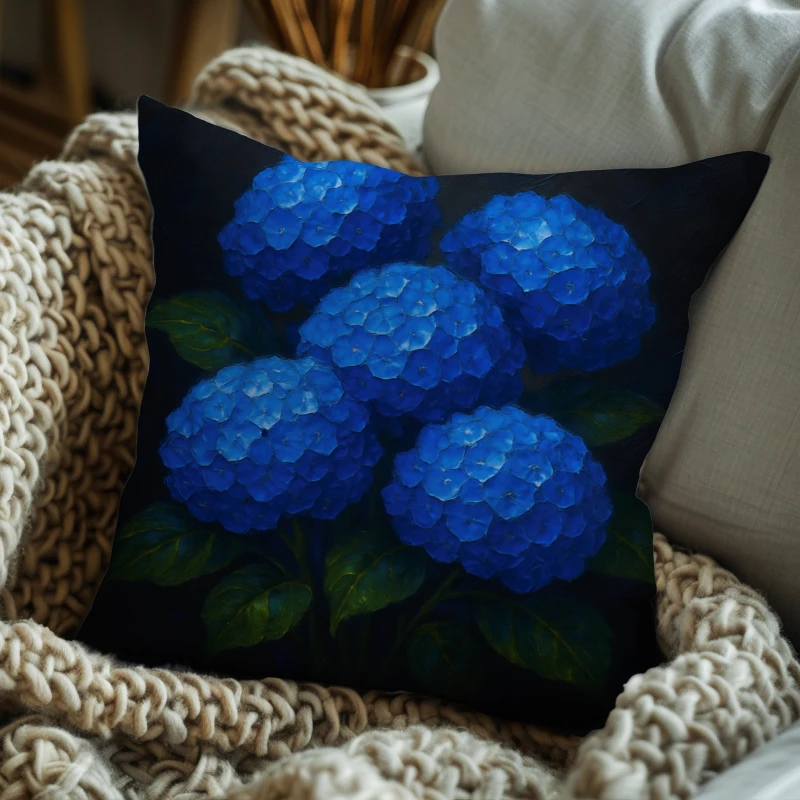 Blue hydrangea impasto pillow on charcoal sofa with dark grey backdrop, silver accents and green leaves