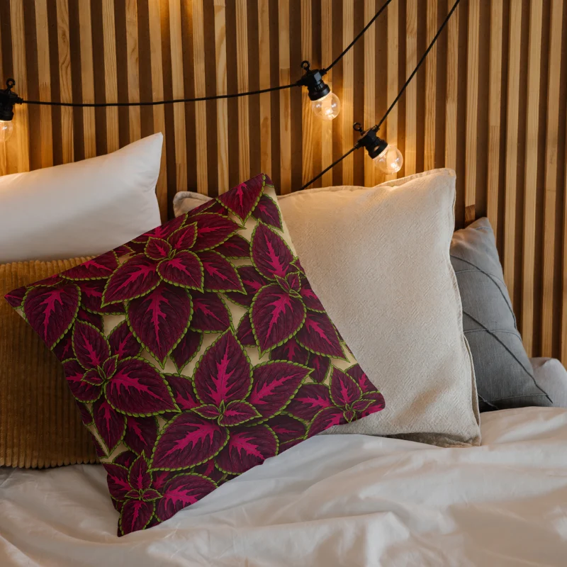 Decorative cushion featuring Begonia Rex foliage in green, pink, and turquoise placed on a cozy bed