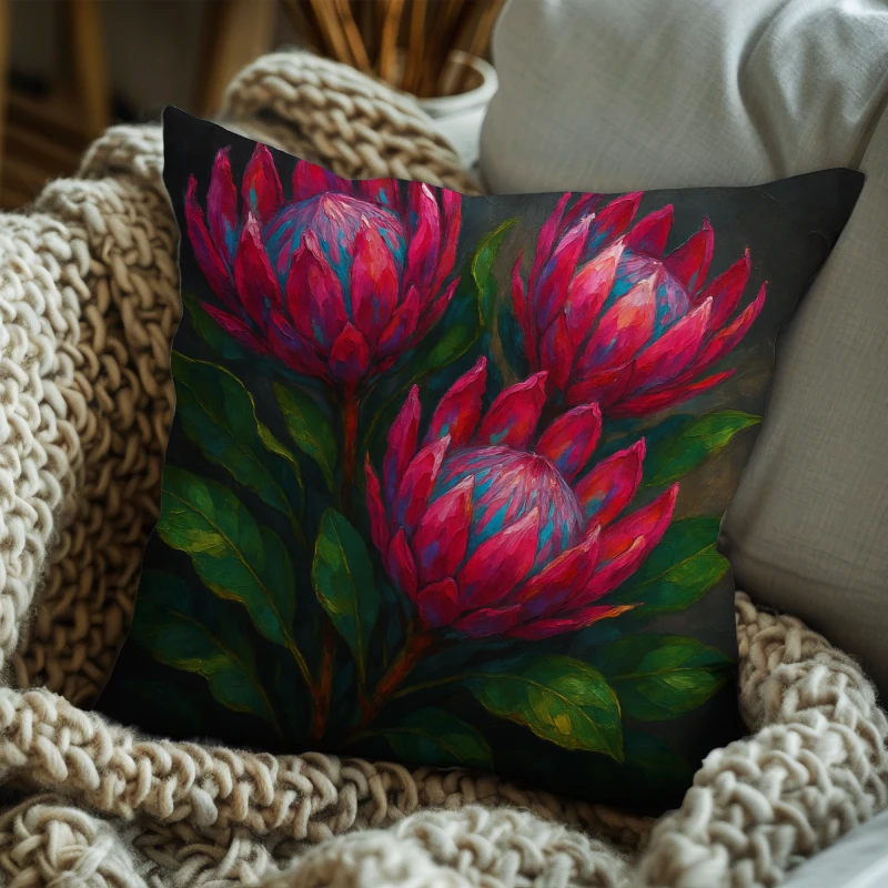 King protea impasto floral pillow styled on deep charcoal sofa, pink petals with lush emerald leaves